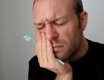 Man Holds Side Of Mouth With Pain - Trade Winds Dental