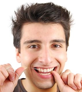 Man Using Dental Floss To Clean Teeth - Trade Winds Dental