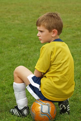Kid Sitting On Soccer Ball - Trade Winds Dental