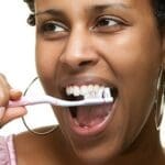 Woman Scrubbing Top Teeth With Tooth Brush - Trade Winds Dental