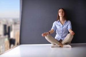 woman meditating against dark wall