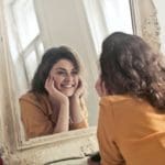 Woman Smiles In Mirror - Trade Winds Dental